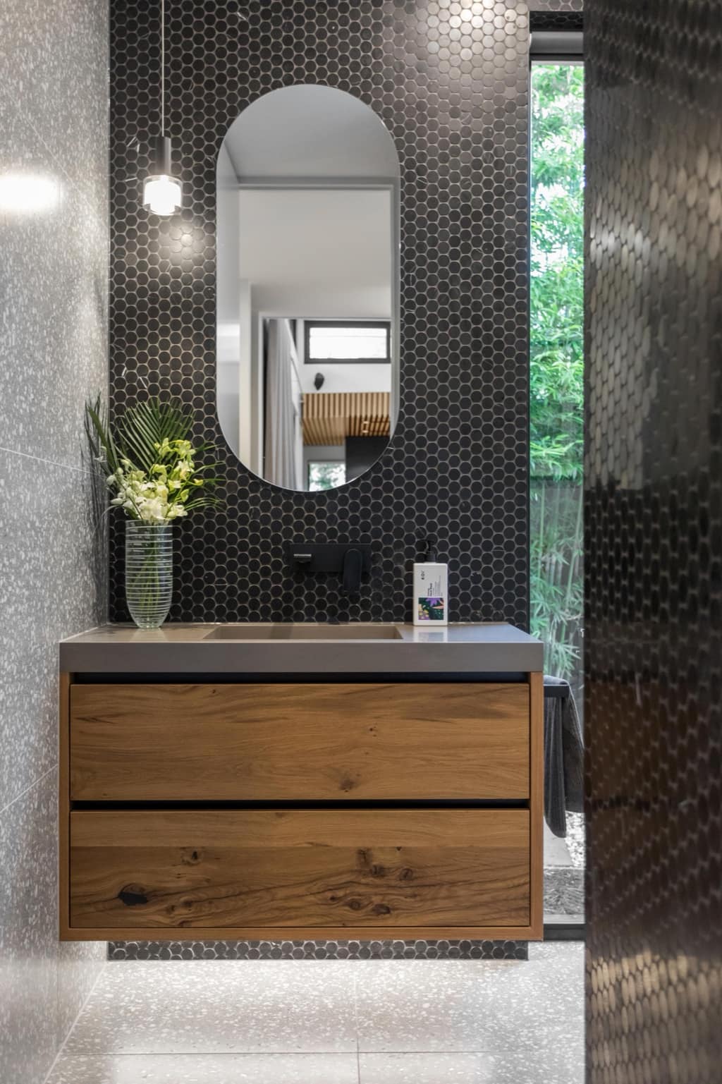 Oak vanity with black hexagon mosaic splashback and a stone benchtop