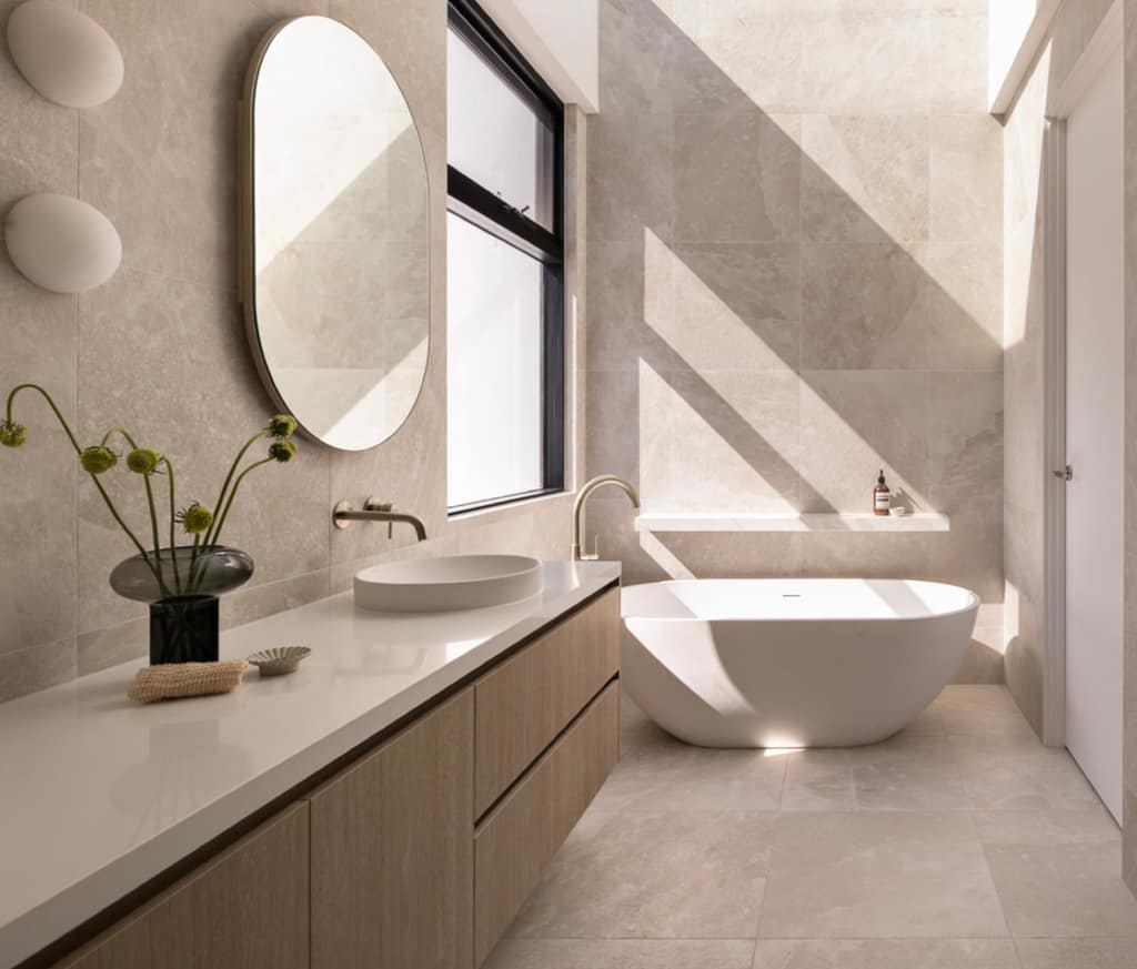 Sunlit travertine bathroom with an oak vanity and freestanding bath