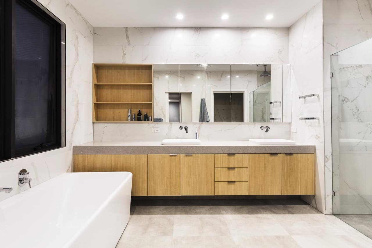 Wide oak floating vanity with twin basins, open shelving and stone benchtop against marble-look walls