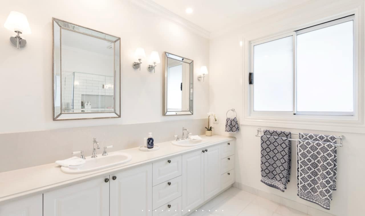 Classic white floor-mounted double vanity with framed mirrors and chrome tapware