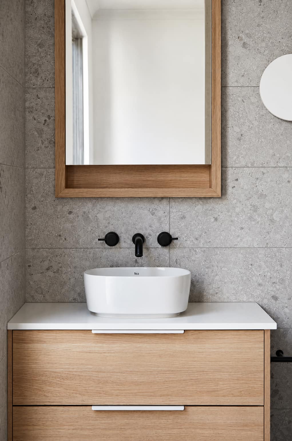 Oak vanity with stone splashback and a white basin