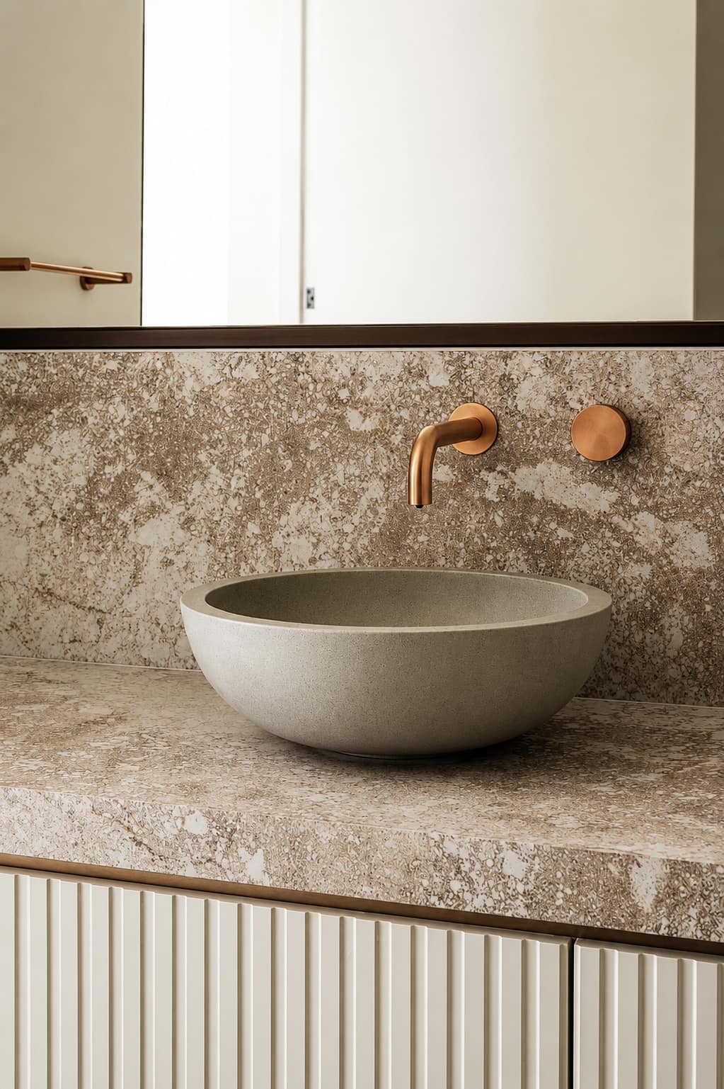 Stone benchtop and splashback with a concrete basin and brass tapware