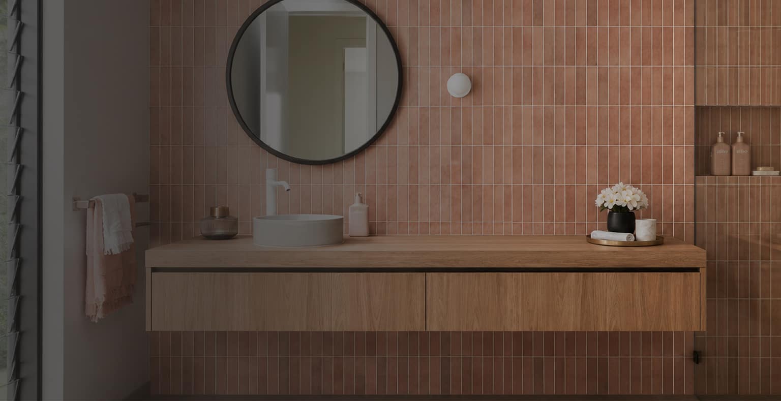 Floating timber vanity with a round mirror against a terracotta finger-tile wall