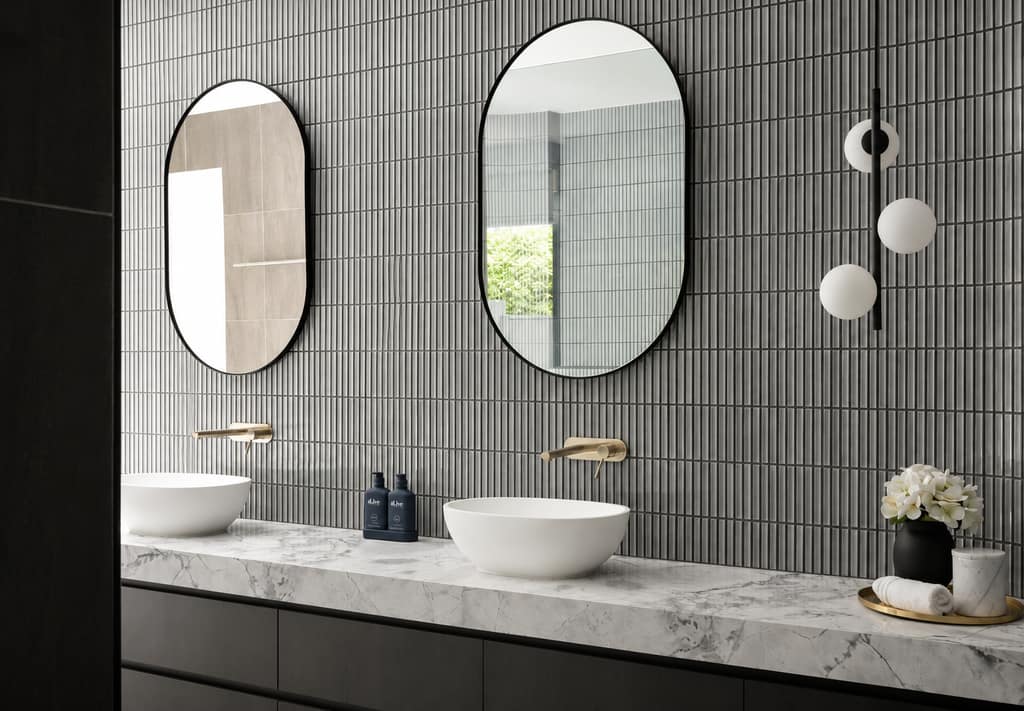 Custom charcoal vanity with a marble benchtop and twin oval mirrors in a Melbourne bathroom